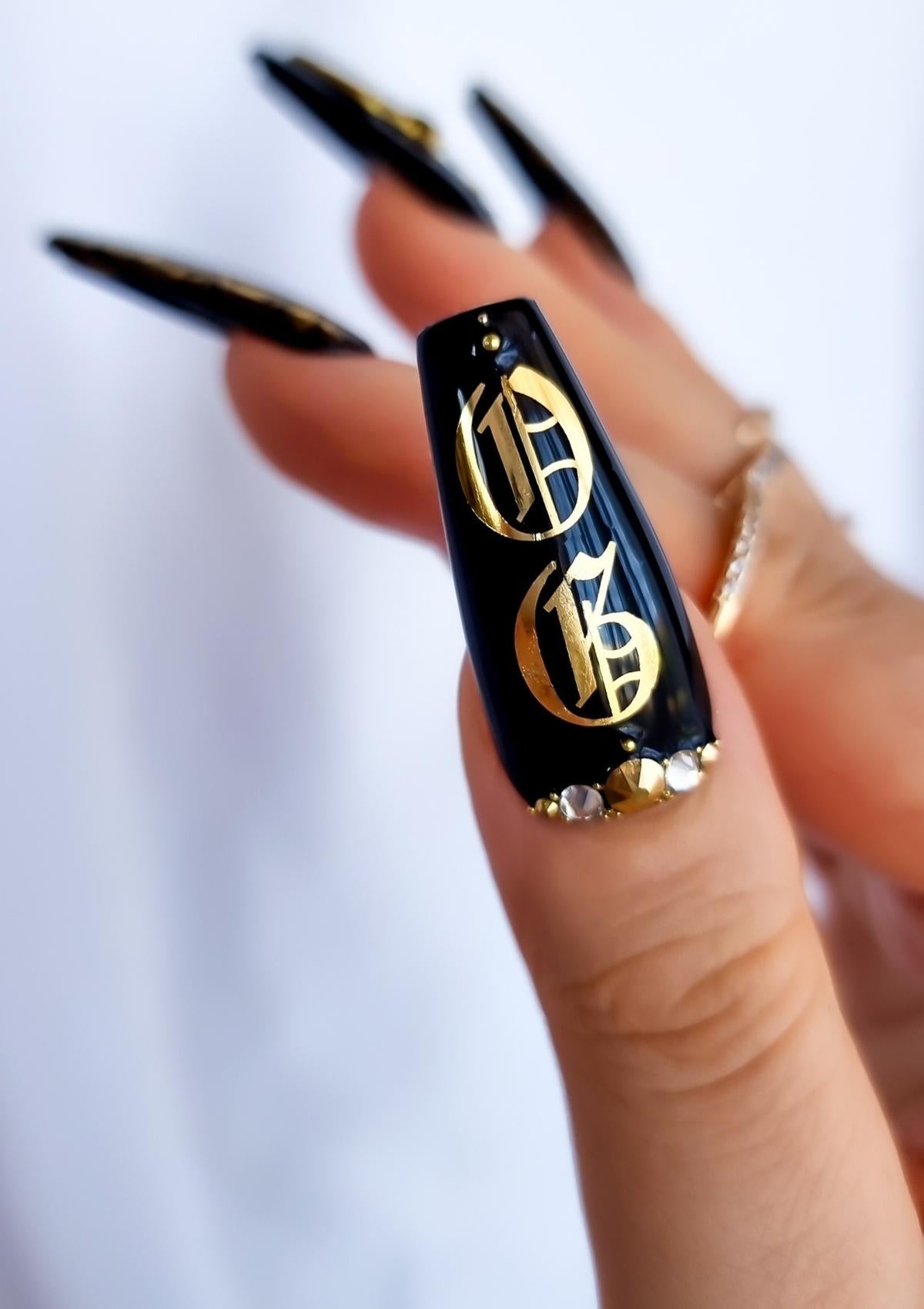 Black thumb nail with gold Old English letters and Swarovski Crystals