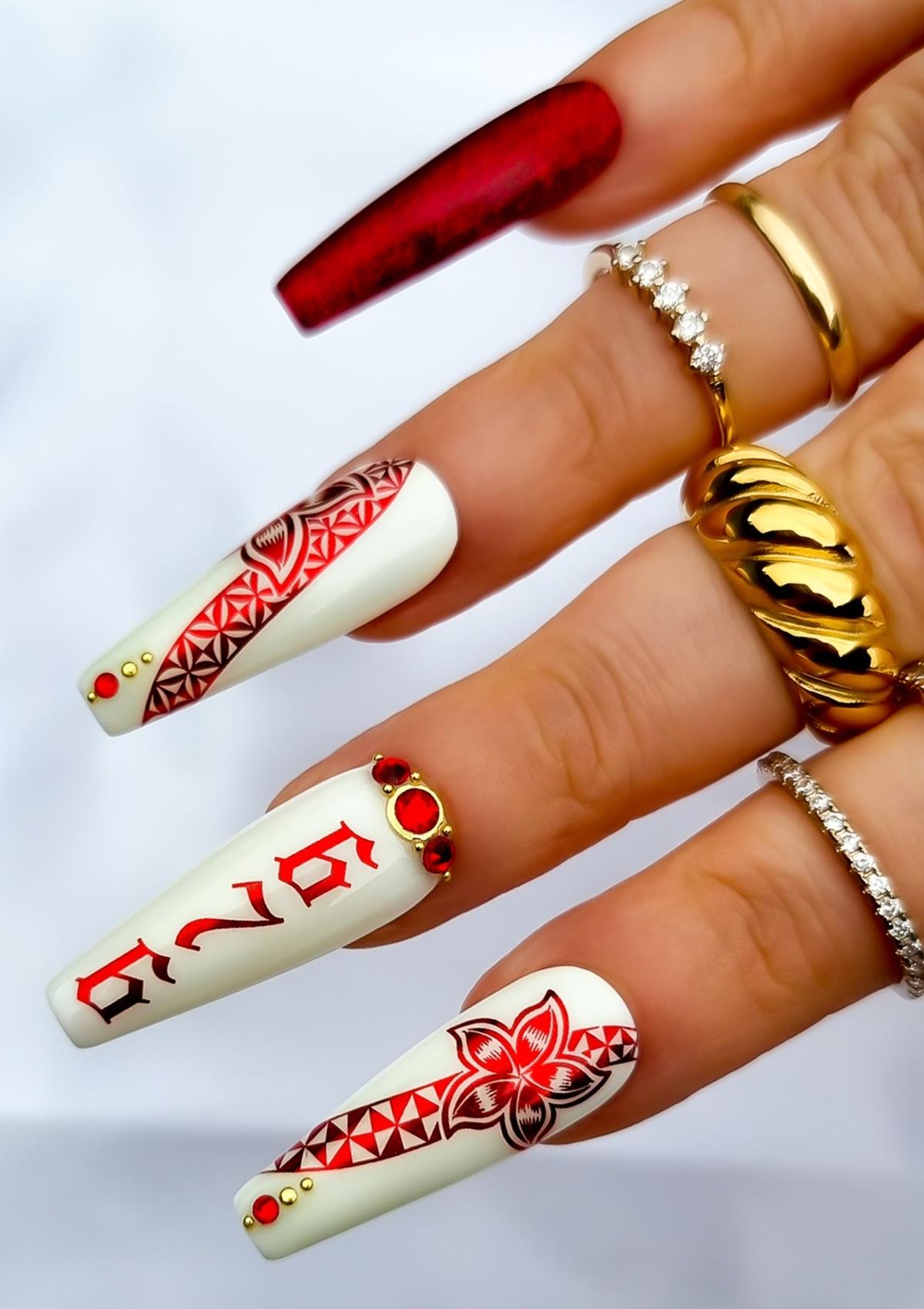 Red and white set of nails with red Tongan patterns , flowers and red and gold accents. Numbers 676 on middle fingernail.  