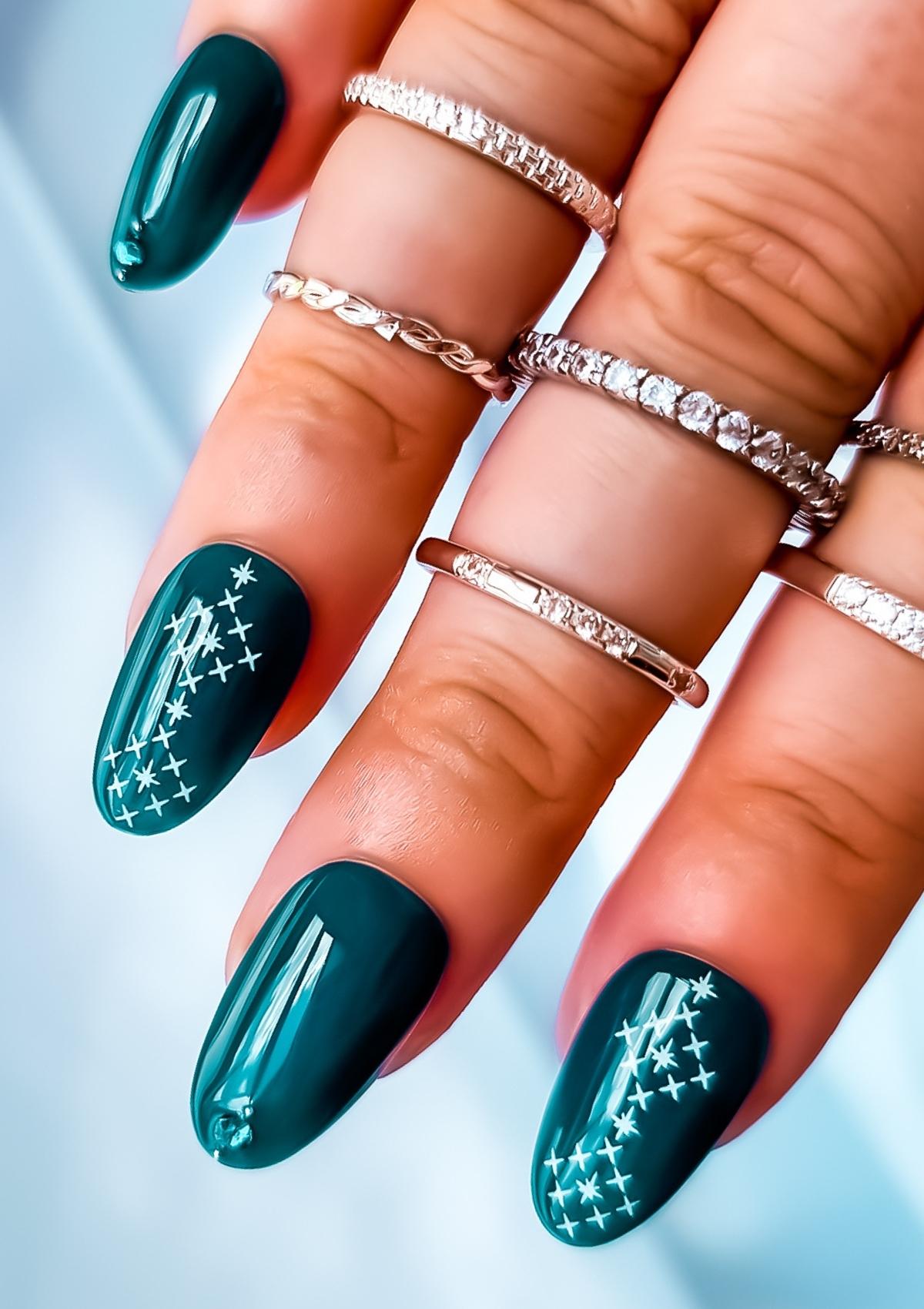 Short oval shaped nails in teal with white Maori nail art on the index and ring fingers. Nail art design in Ngā Whetu by Adrienne Whitewood.  