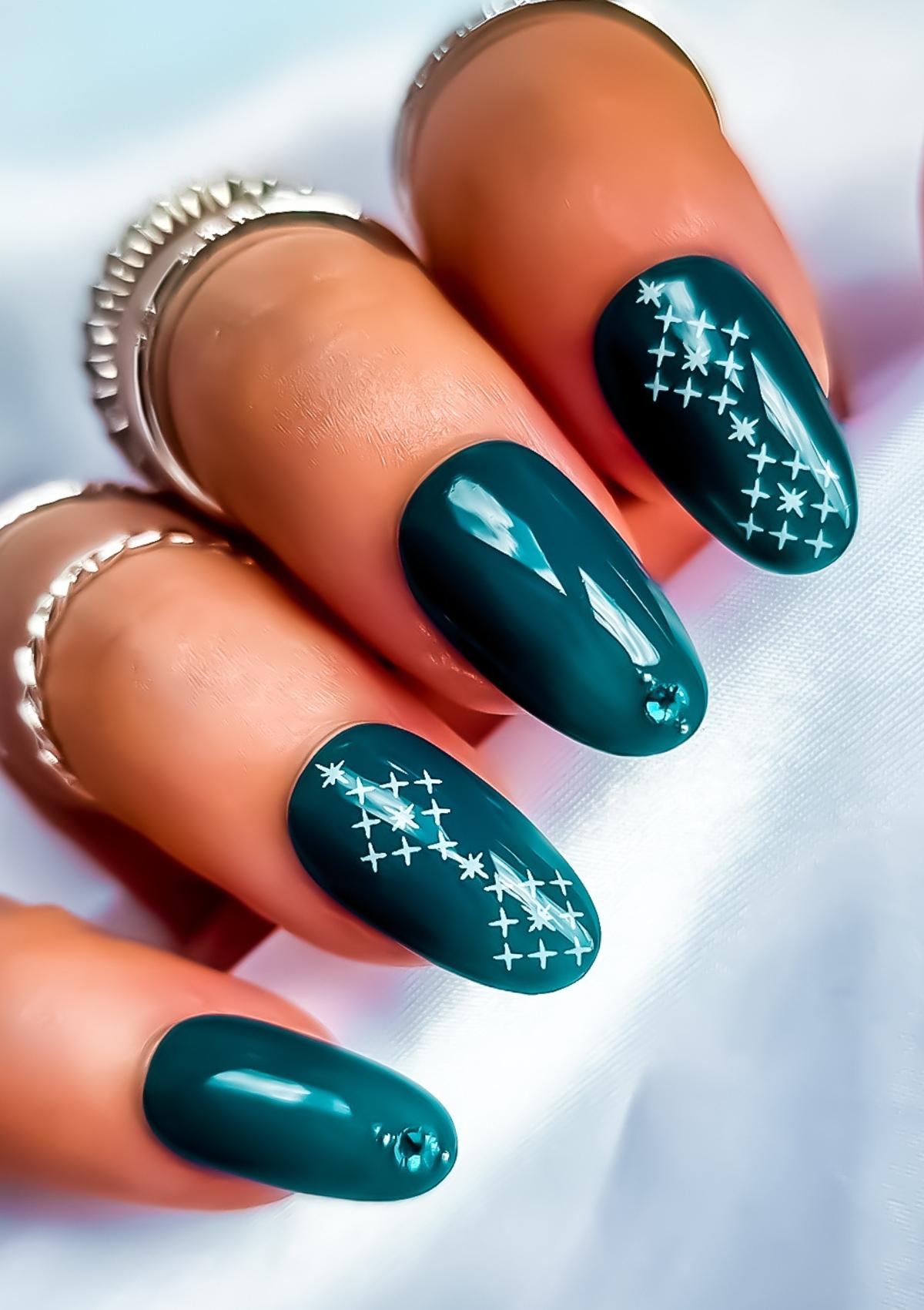 Short oval shaped nails in teal with white Maori nail art on the index and ring fingers. Nail art design in Ngā Whetu by Adrienne Whitewood.  