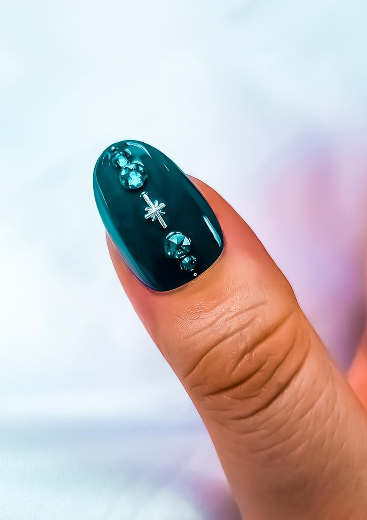 Short oval shaped  thumb nail in teal with silver star charm and teal crystals.