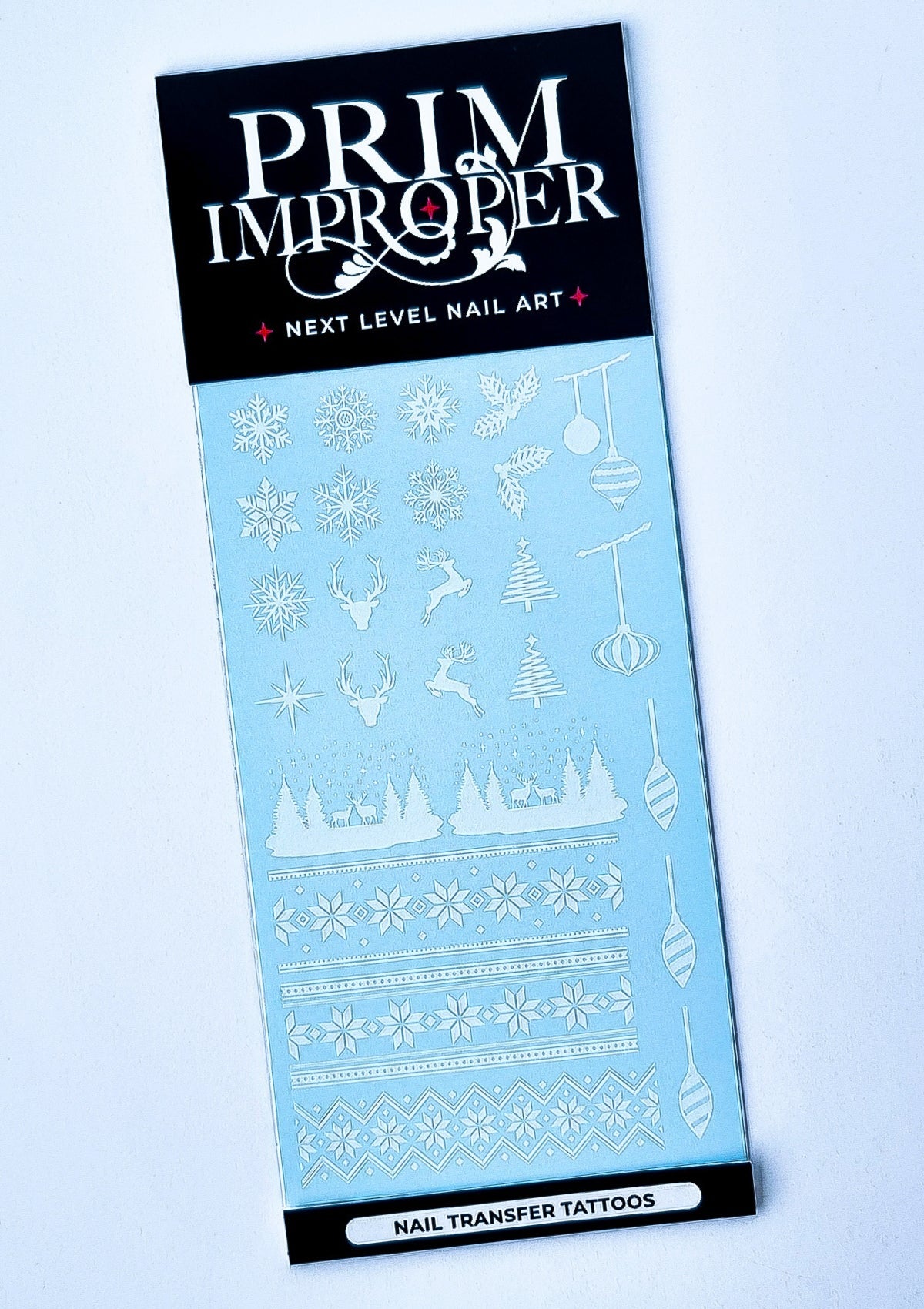 Sheet of white Christmas Nail Transfer Tattoos featuring Nordic sweater patterns, snowflakes, holly, reindeer, stars, Christmas trees and baubles 